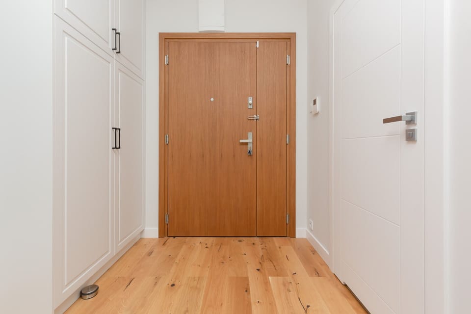 The apartment entrance with a sturdy wooden door and a welcoming minimalist design.

