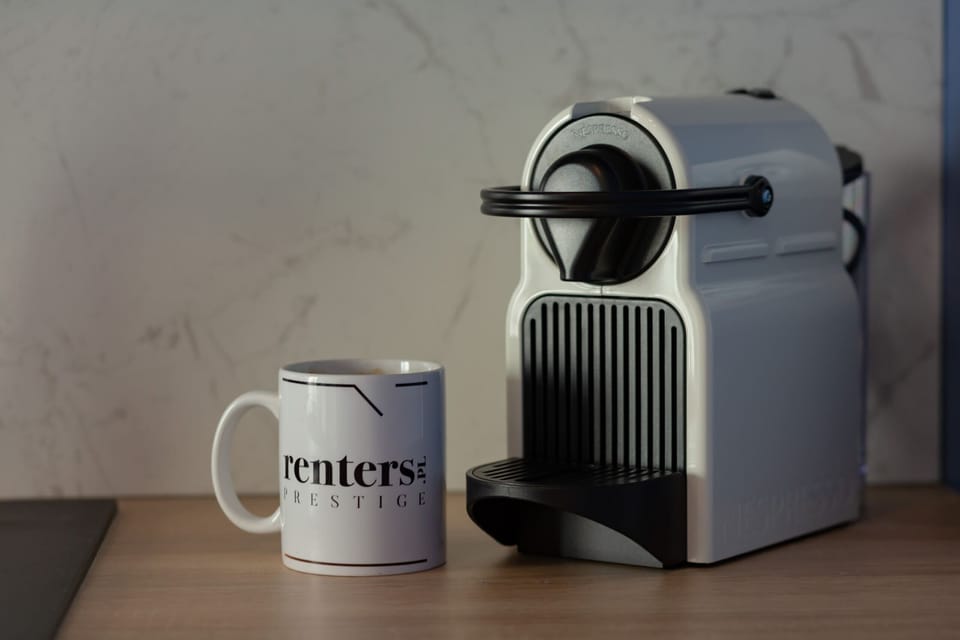 A sleek coffee machine accompanied by a branded mug, perfect for your morning brew.
