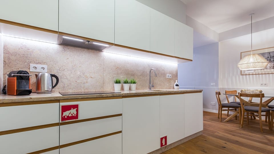 Prepare delightful meals in this sleek, modern kitchen, featuring pristine countertops and ample under-cabinet lighting, then gather around the inviting dining table for shared moments and delicious food. Enjoy the convenience of home cooking and memorabl