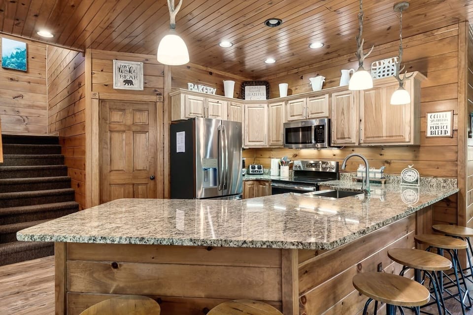 Kitchen is stocked with cooking gear and utensils. Pull up a stool at the kitchen bar countertop.