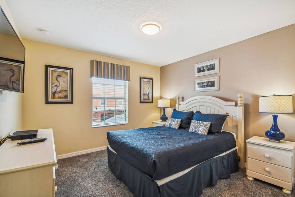 This cozy bedroom, with its plush navy bedspread and stylish accent pillows, offers a restful atmosphere. Soft lighting from the bedside lamps and a large window create a warm glow, perfect for unwinding after a day of adventure.