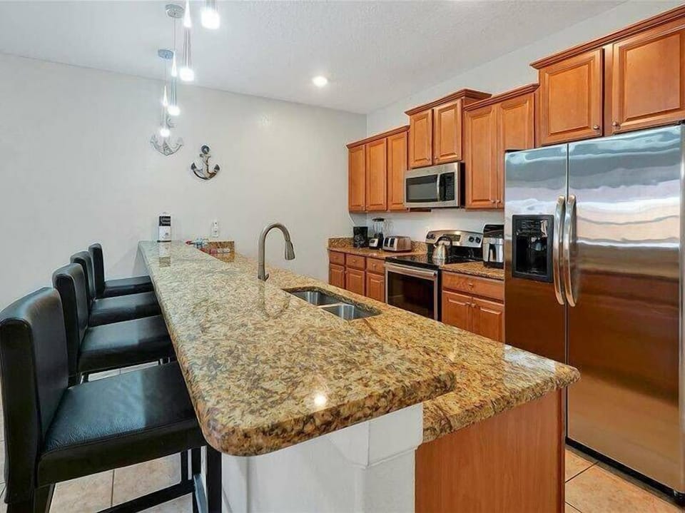 Experience the warmth of this kitchen with granite countertops and wooden cabinetry. Modern stainless steel appliances make cooking easy, while stylish bar stools create a perfect spot for casual meals to start your mornings.