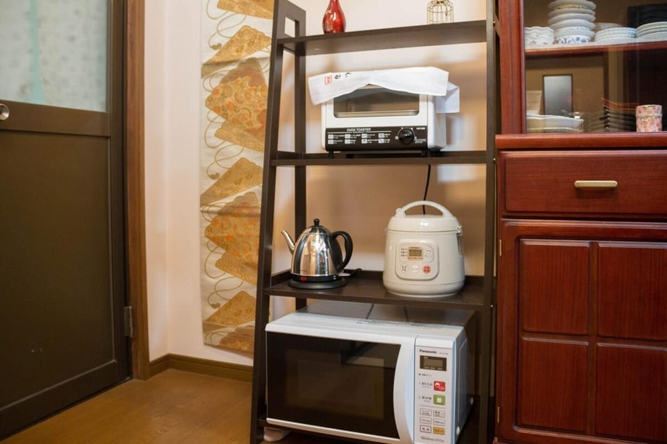 A kitchen with a rice cooker, a microwave, a toaster, an electric kettle