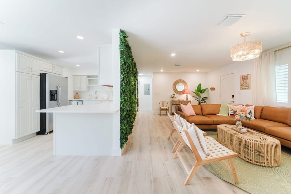 Relax after a day at the beach in this designer living space featuring a plush sectional, oversized Smart TV, and light-filled coastal interiors