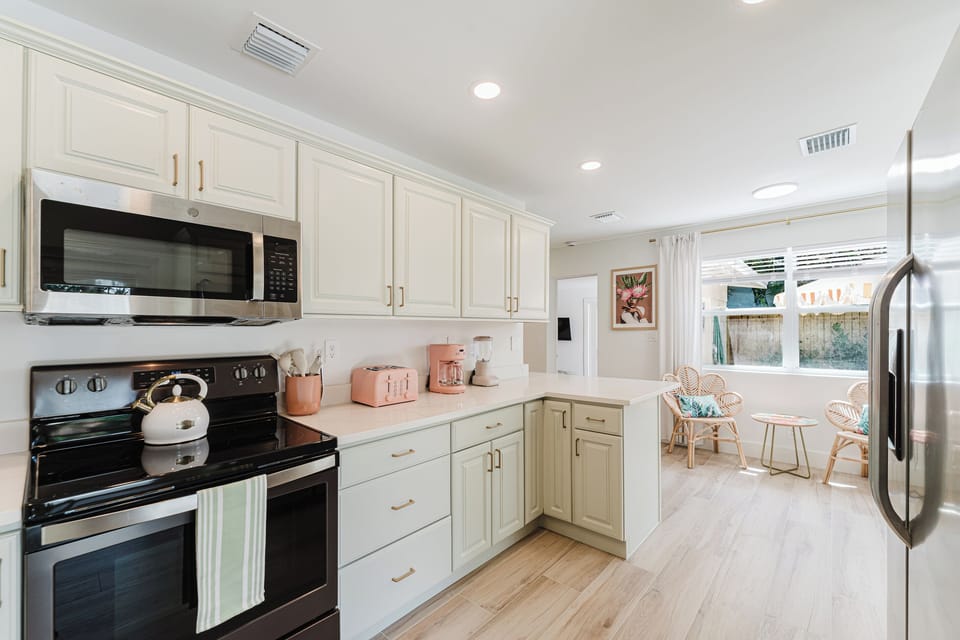 A beautifully updated kitchen designed with style and function in mind, offering elegant sage cabinetry, quartz countertops, champagne gold fixtures, a farmhouse sink, stainless steel appliances, and premium small appliances for your stay.