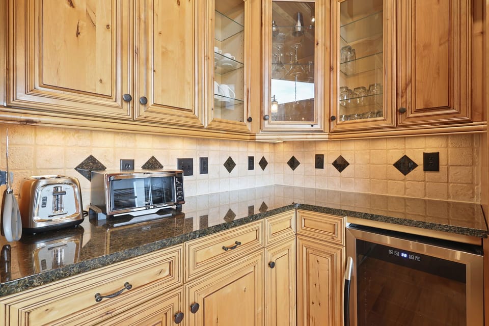 Right by the fridge is the prep station with toaster, mini oven, dishes, silverware and glasses.