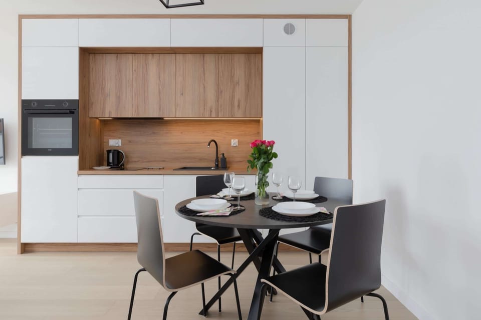A bright kitchen with white cabinets and wooden accents, leading into a dining and living area.