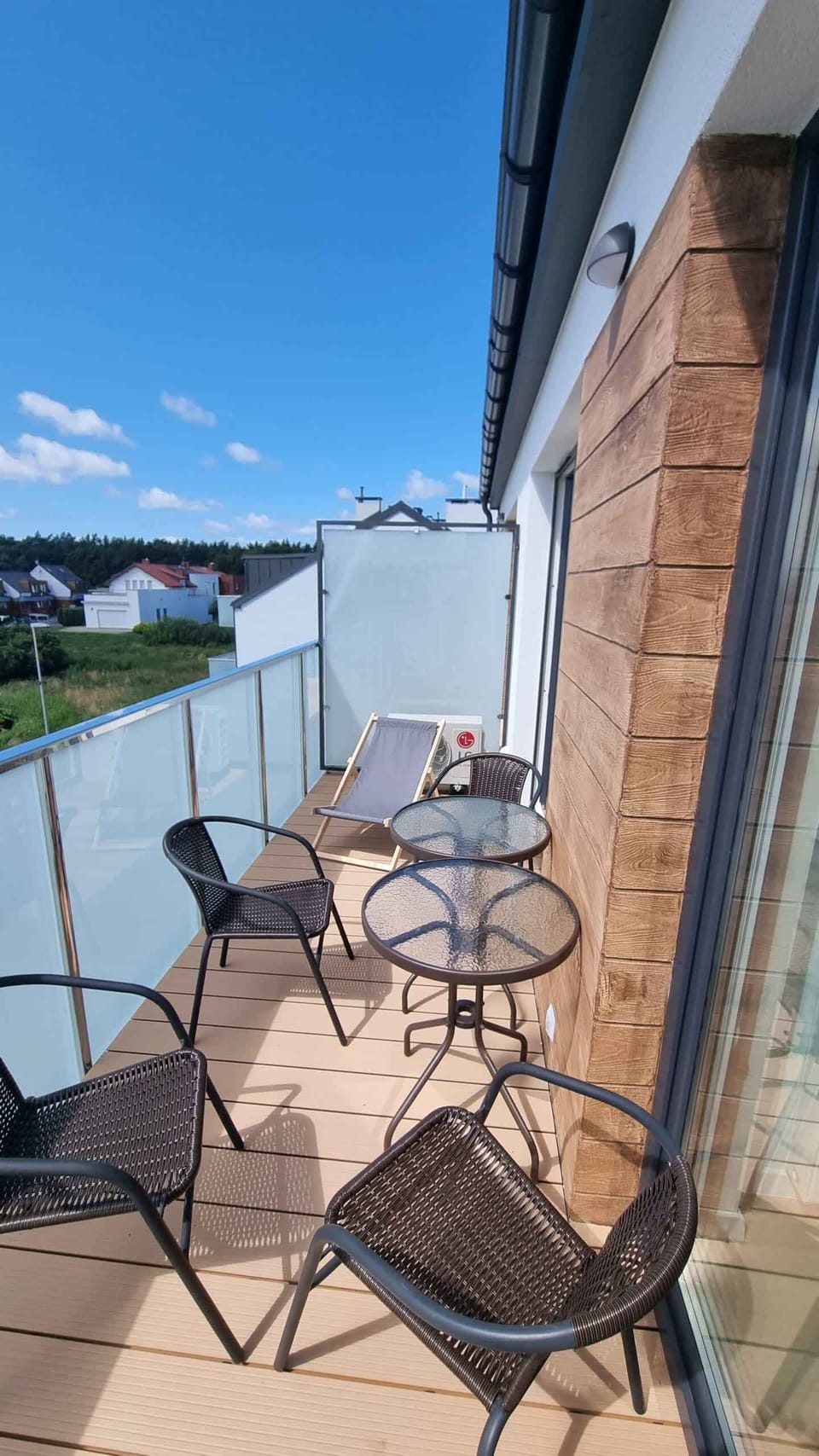 An outdoor balcony with a small table, chairs, and a view of the surroundings.