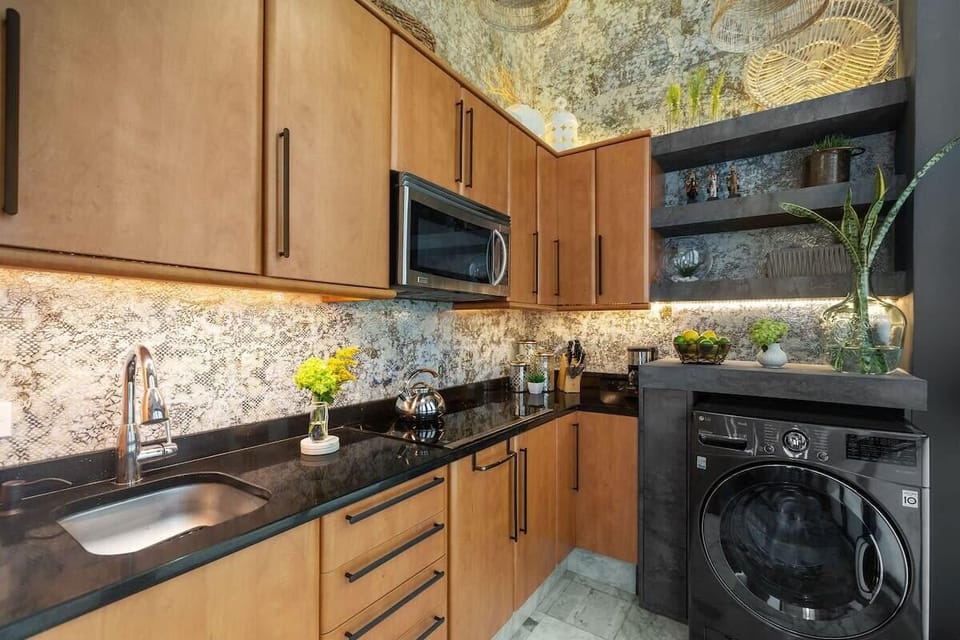 Eclectic and fully equipped kitchen has a microwave, coffee maker, full size fridge, and induction stove. There is a washer/dryer combo as well.