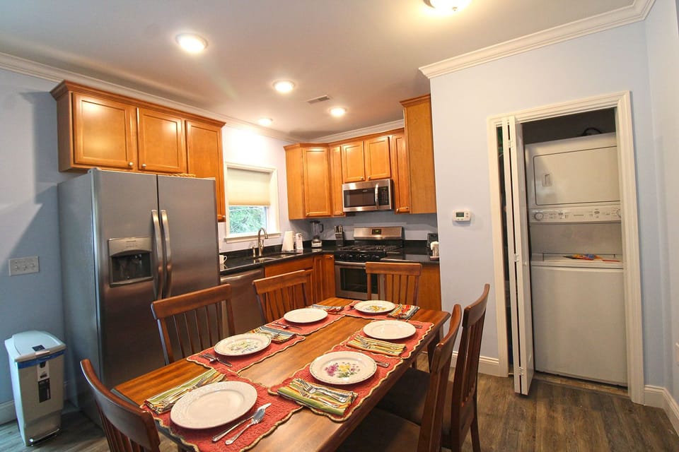 Bright kitchen and dining area featuring stainless steel appliances, wood cabinets, and a dining table. Convenient for preparing meals near Great Smoky Mountain National Park adventures.
