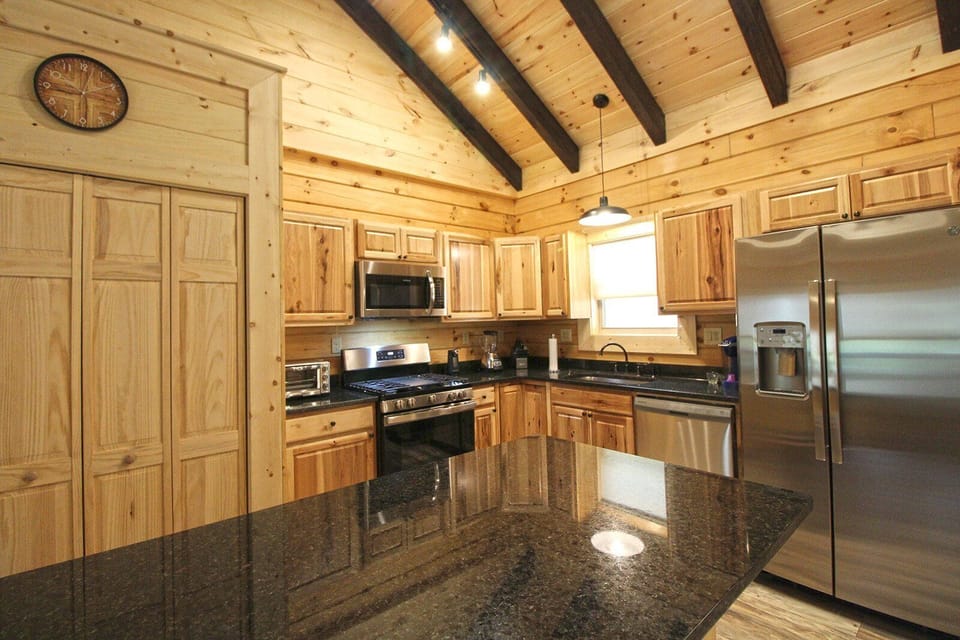 Bright kitchen workspace with granite counters, stainless appliances, and natural wood finishes throughout the cabin interior.