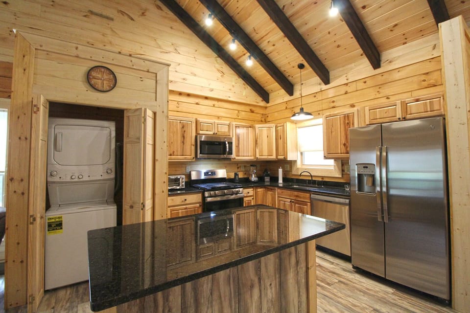 Spacious kitchen showcasing large granite island, wood cabinetry, and open layout connecting to the main living space.