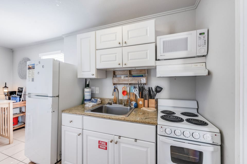 Cook your favorite meals in this fully equipped kitchen with white cabinets, granite countertops, and all essential appliances for a comfortable stay.