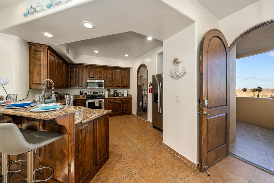 Fully equipped kitchen with granite countertops, stainless steel appliances, and easy access to outdoor dining.