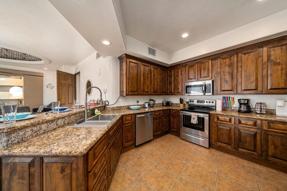 Fully stocked kitchen featuring stainless steel appliances, coffee station, and generous granite counter space