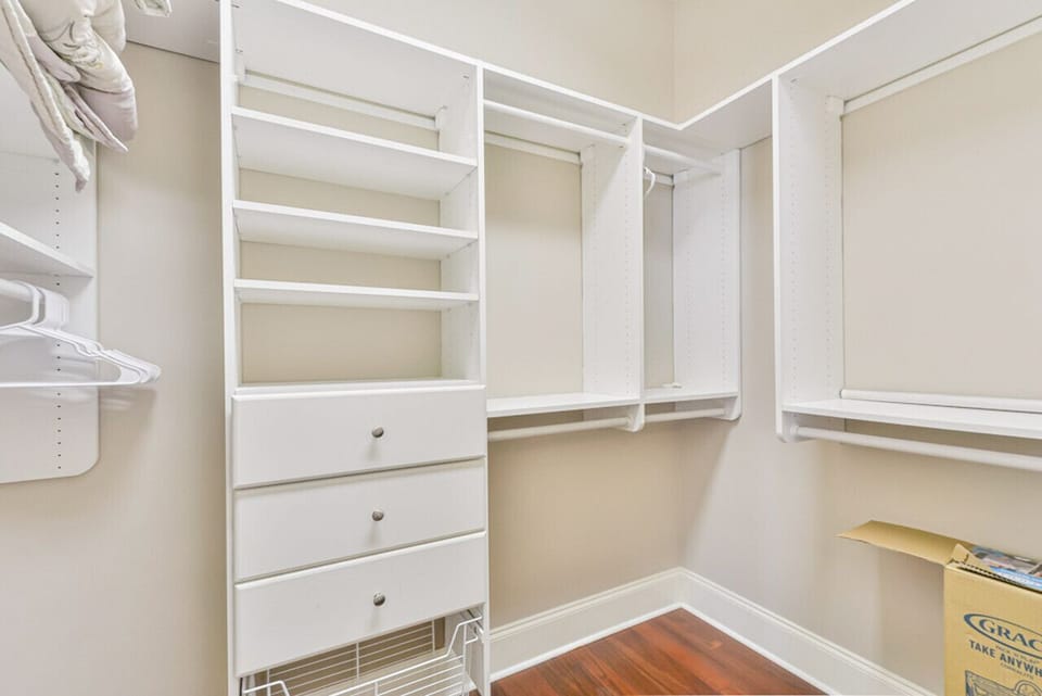 The spacious white closet features well-organized shelves and drawers, offering ample storage for a tidy and efficient solution to keep personal items.