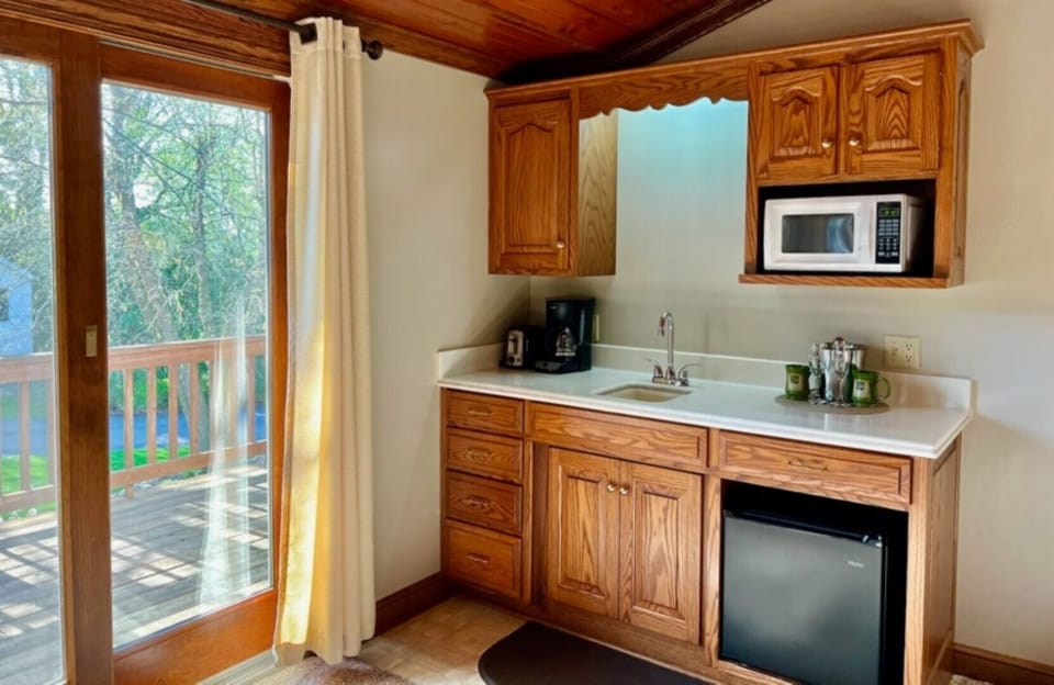 Kitchenette with small fridge, microwave, Keurig coffee maker and dishes.