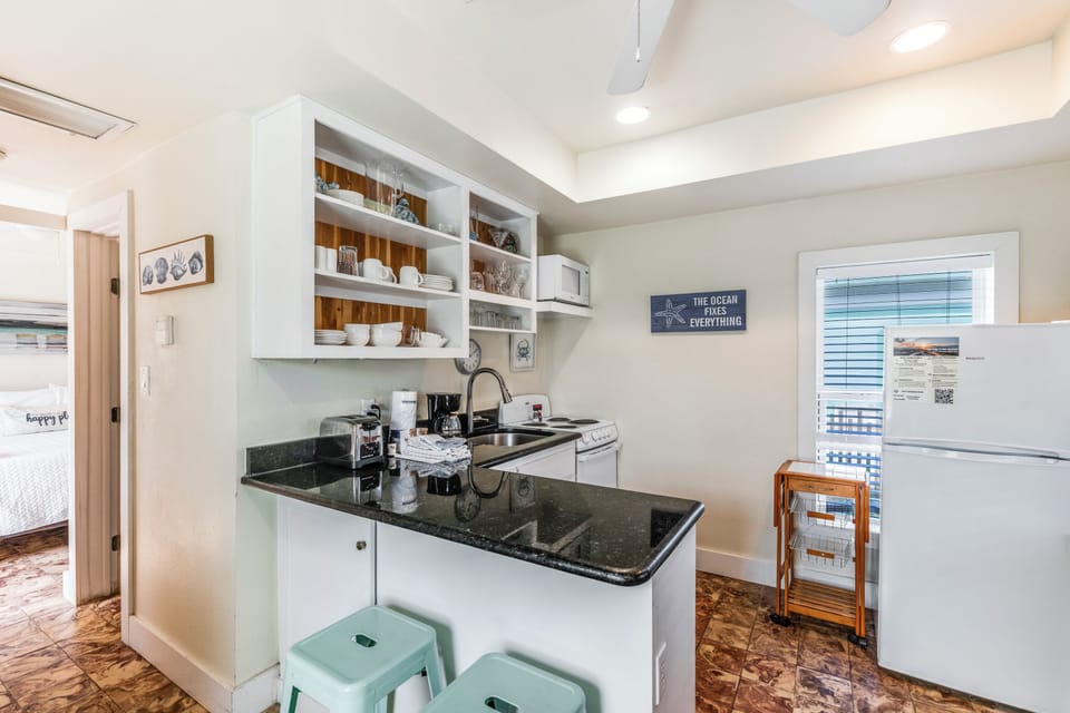 Your bright kitchen features granite counters, open shelving, and everything you need to create delicious meals during your coastal getaway.