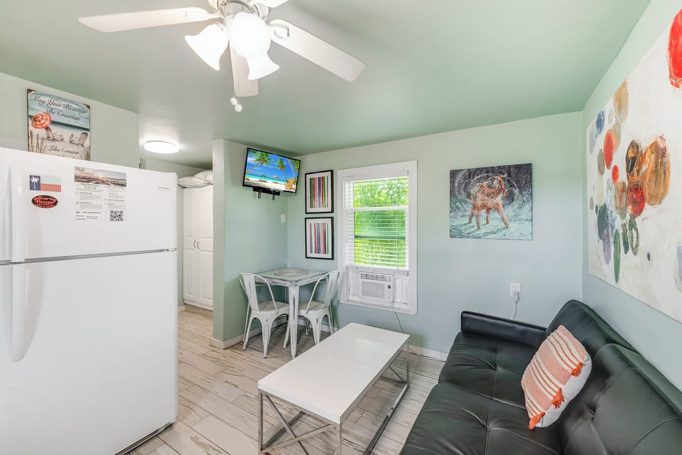 Your cozy retreat features a stylish living space with soft mint walls, modern furnishings, and cheerful artwork creating the perfect atmosphere for relaxation.