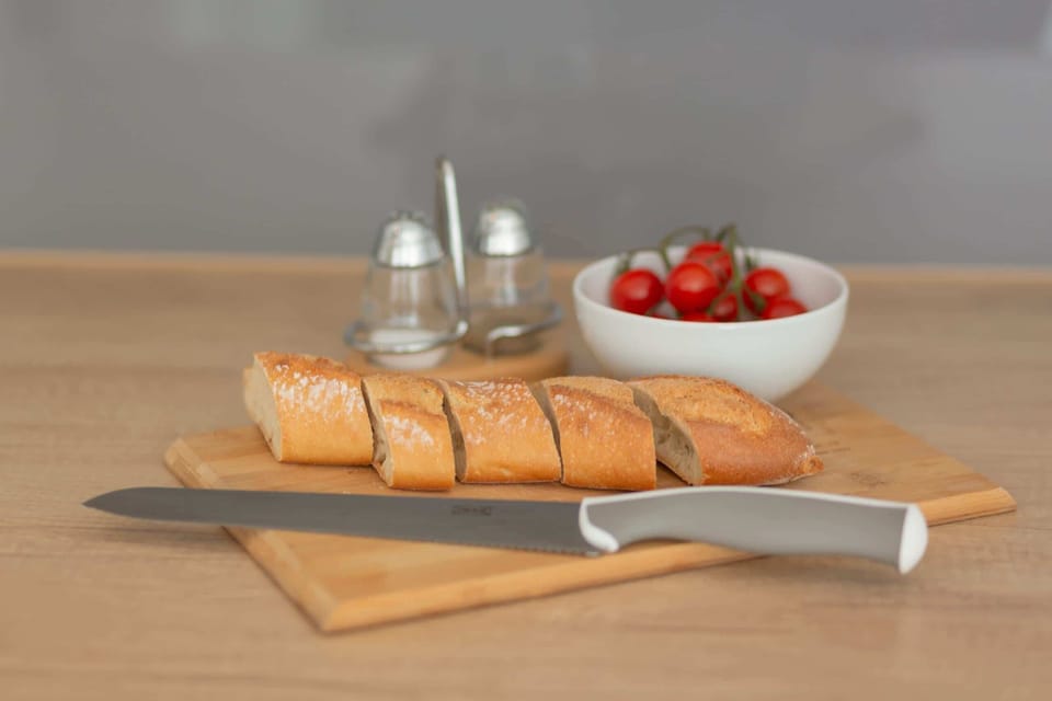 A breakfast setup on a cutting board, featuring a baguette, butter, and fresh cherry tomatoes, adding a homely and inviting touch to the kitchen area.