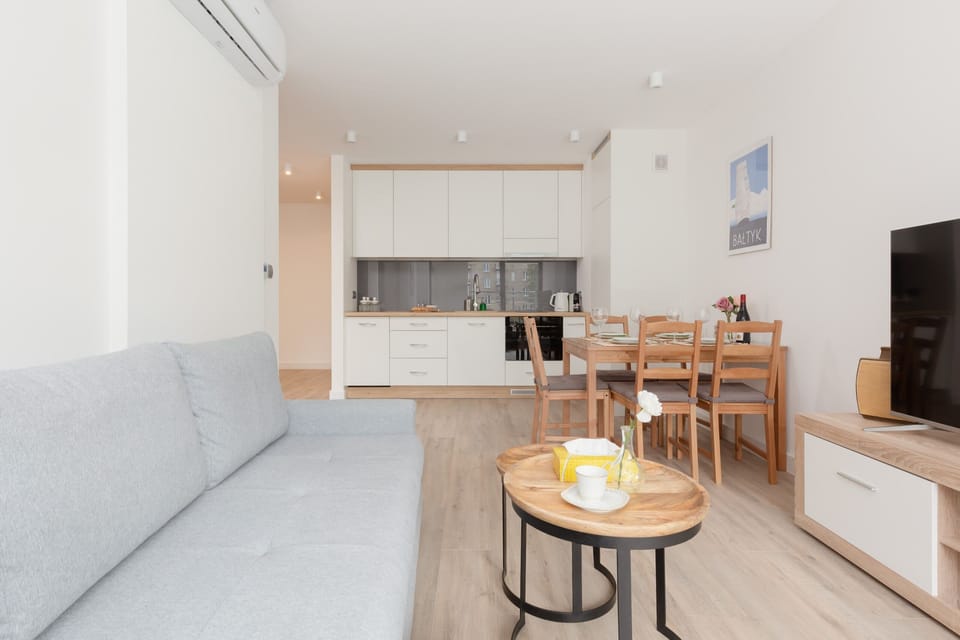Another angle of the living room, showing a gray sofa and a flat-screen TV on a modern wooden TV stand, offering a comfortable entertainment space.