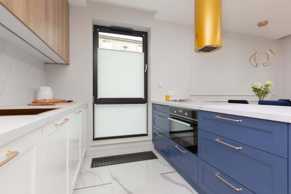 A functional kitchenette with navy blue and white cabinets that match the decor of the rest of the room.