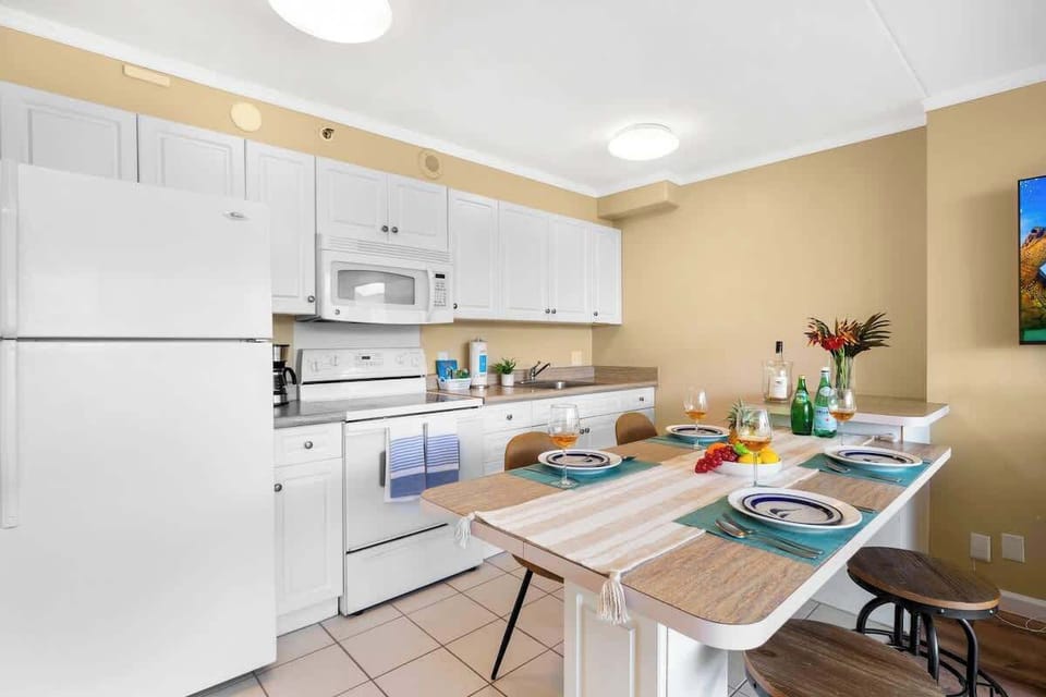 Prepare meals easily in this full kitchen featuring clean white cabinets and appliances, paired with a convenient dining table.