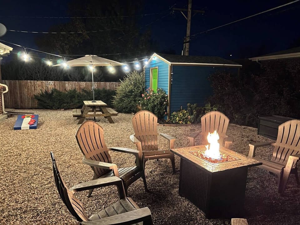 - Unwind under the stars around a glowing fire pit with comfy Adirondack chairs & cozy lighting
- Roast marshmallows, or enjoy drinks in this inviting backyard retreat
- Fun extras like cornhole, a picnic table, & a bright shed complete the laid back