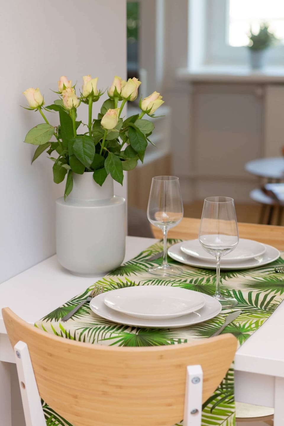 Close-up of a dining table with kitchenware and a decorative vase containing flowers.