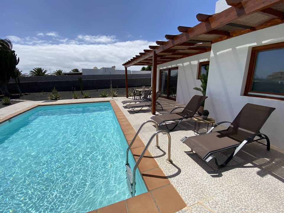 Private pool with dining area and sun loungers.