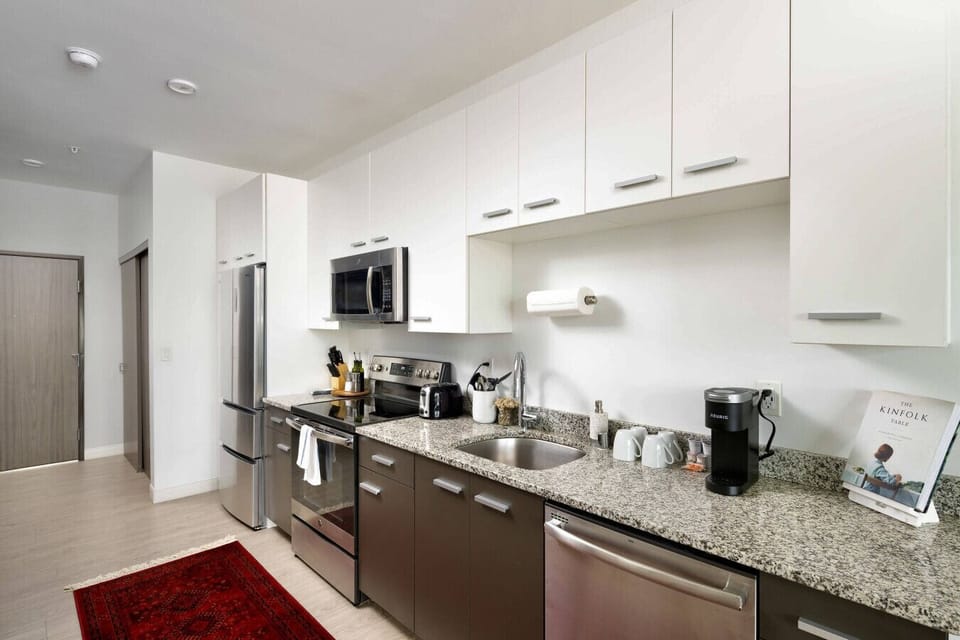 Prepare home-cooked meals or a quick morning brew in our pristine, fully-equipped modern kitchen featuring stainless steel appliances.