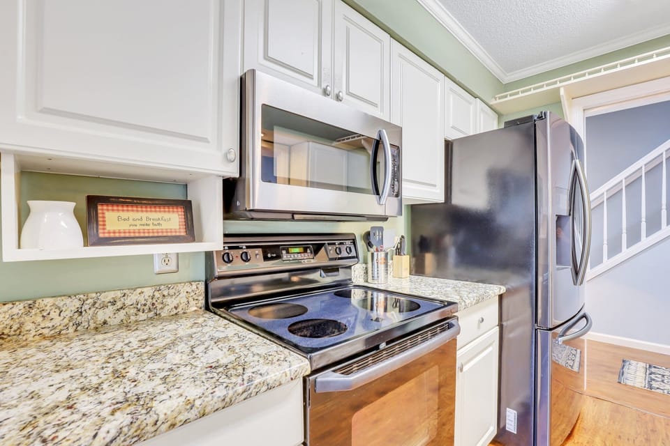 The fully stocked kitchen has stainless steel appliances and granite counter tops with a window cut out that gives the kitchen a feeling of an open floor plan while still maintaining privacy.