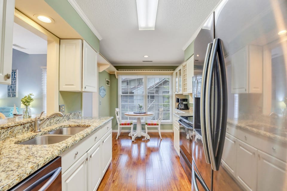 The fully stocked kitchen has stainless steel appliances and granite counter tops with a window cut out that gives the kitchen a feeling of an open floor plan while still maintaining privacy.