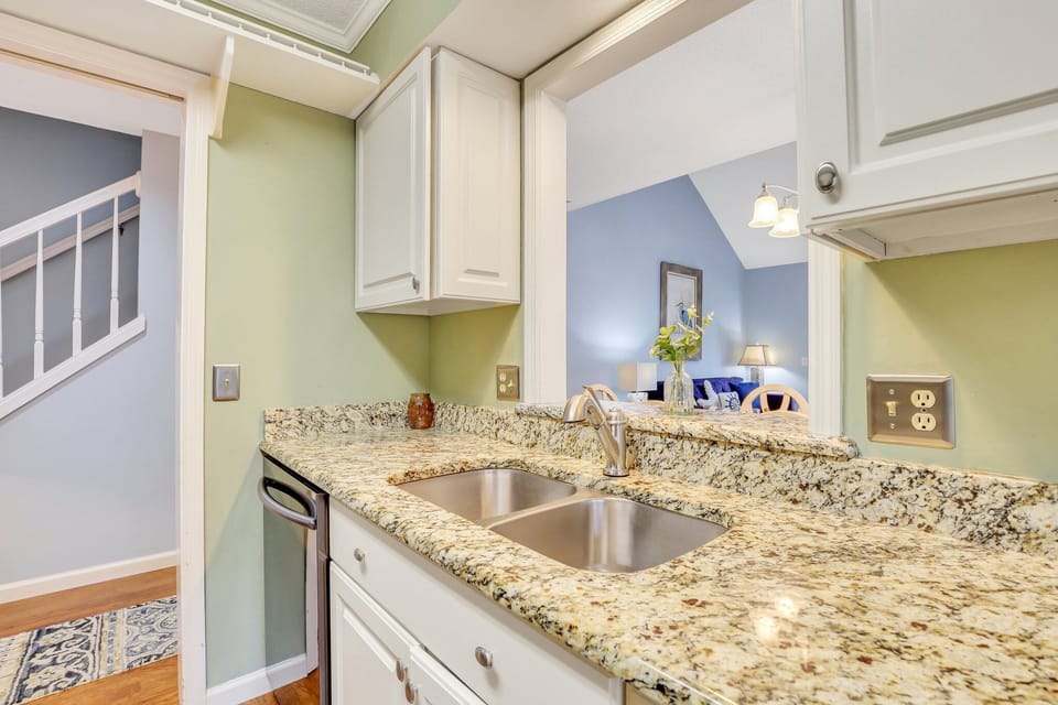 The fully stocked kitchen has stainless steel appliances and granite counter tops with a window cut out that gives the kitchen a feeling of an open floor plan while still maintaining privacy.