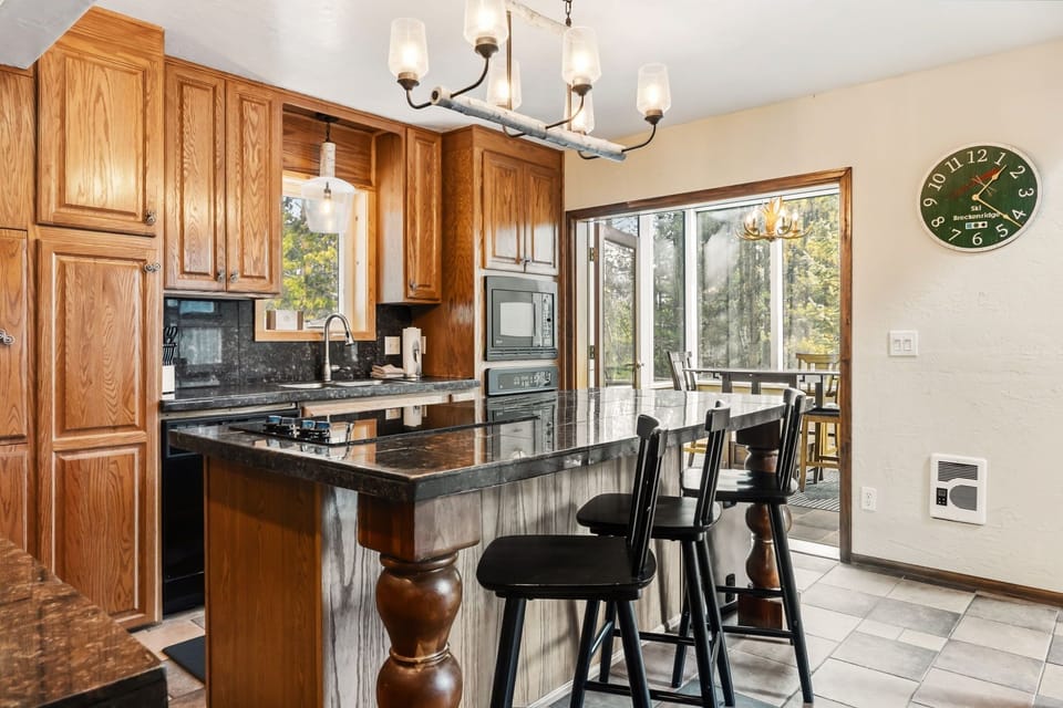 Your gourmet kitchen features granite countertops, rich oak cabinetry, and a breakfast bar perfect for morning coffee while enjoying forest views through the large windows.