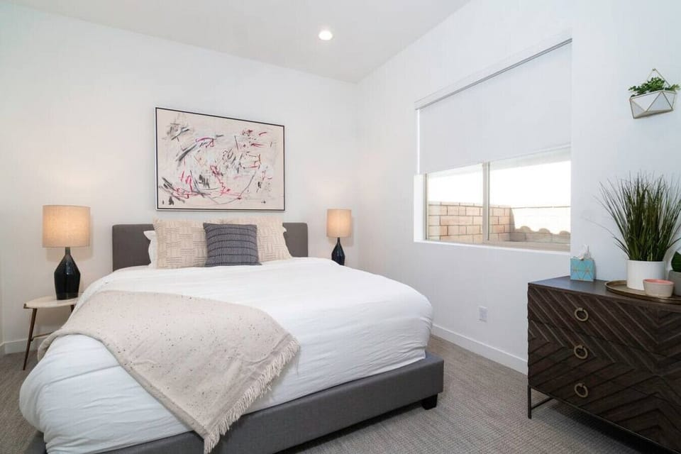 Inviting bedroom w/ plush bed, warm lighting & wide window