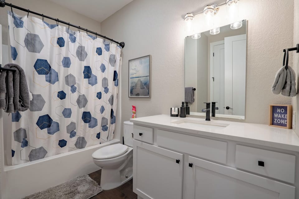 Bunk room bath accessible from hallway next to room with shower/tub combo & sink
