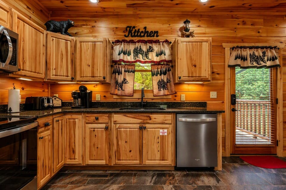 Quiet dishwasher complemented by beautiful, handcrafted bear‑themed curtains that add a personal Smoky Mountain touch