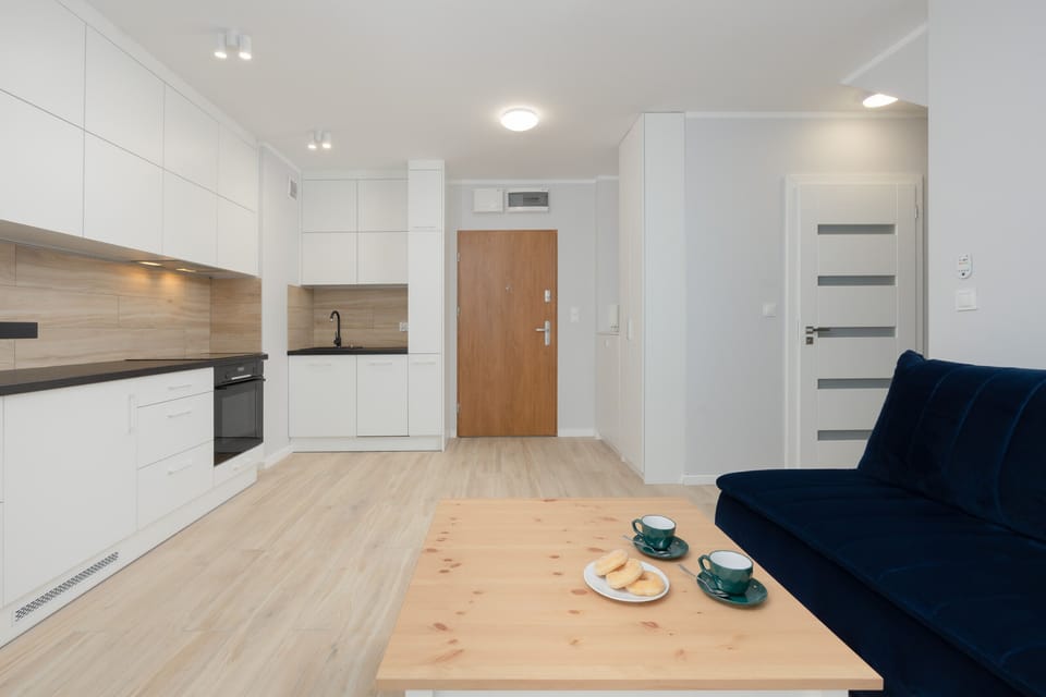 An open kitchen design with sleek white cabinets, black countertops.