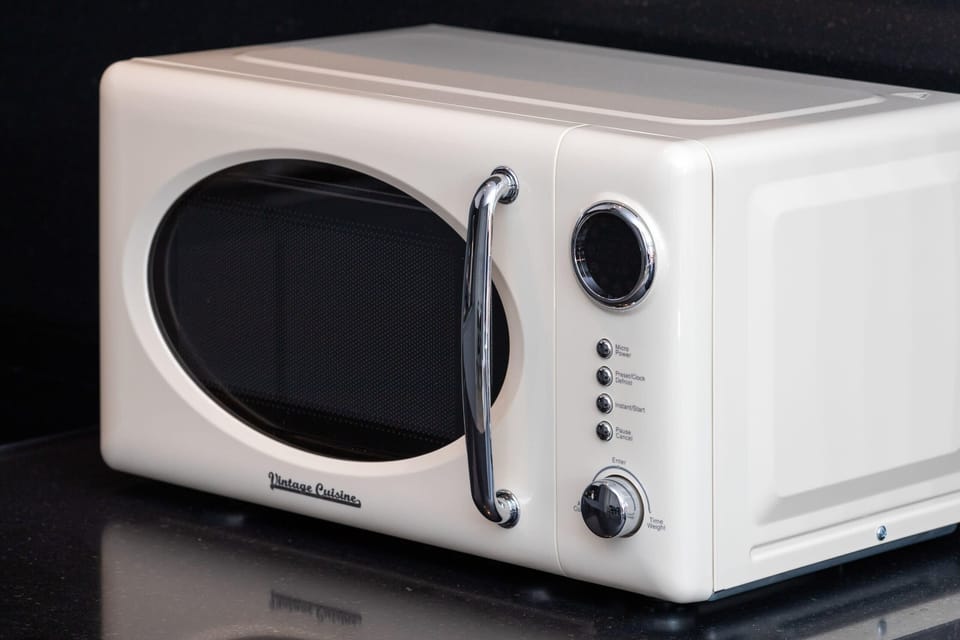 A close-up of a vintage-style cream-colored microwave placed on the kitchen counter.