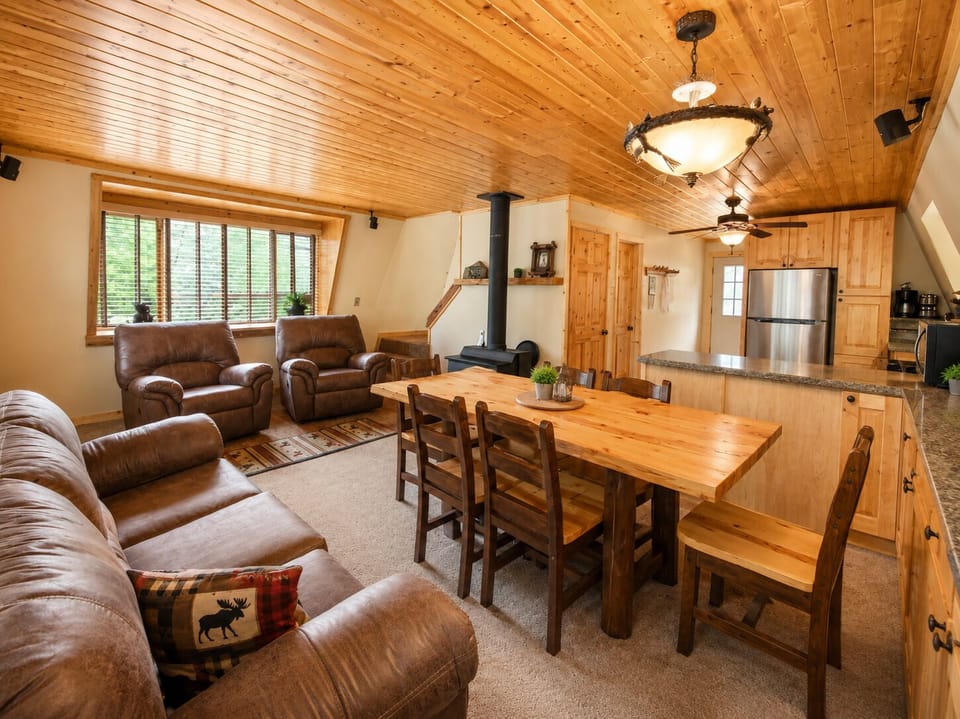 Warm knotty pine ceilings, leather seating, and rustic decor create your cozy mountain retreat. Gather at the handcrafted dining table, unwind by the wood stove, and enjoy seamless open-plan living.