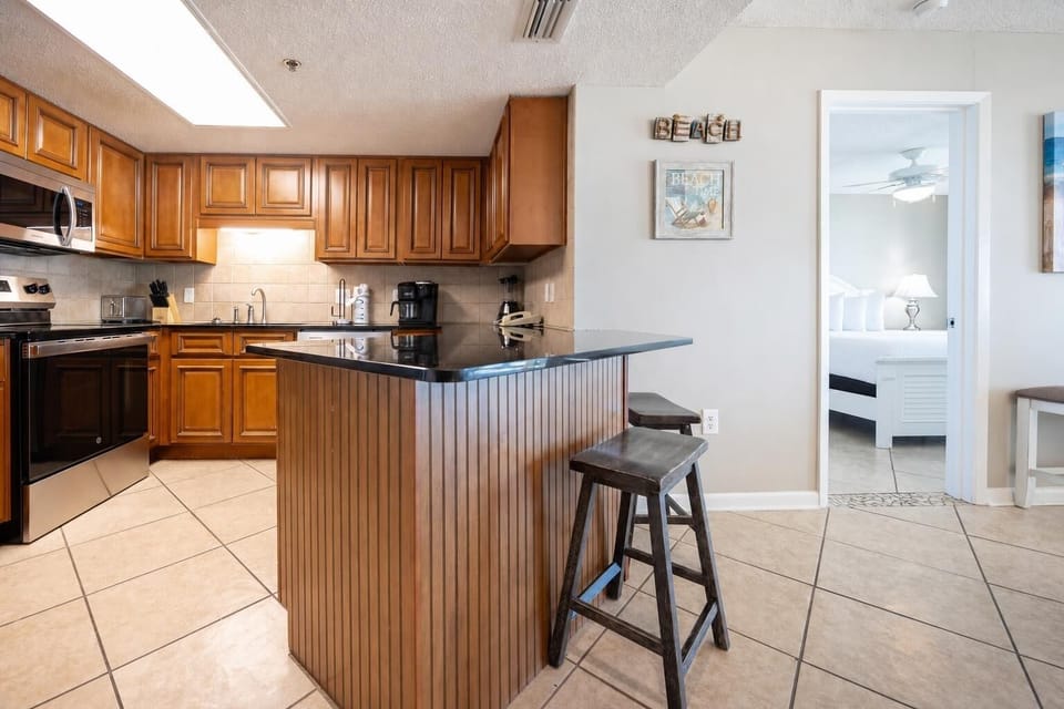 Warm wooden cabinetry complements the dark countertops and stainless appliances, creating a welcoming kitchen space