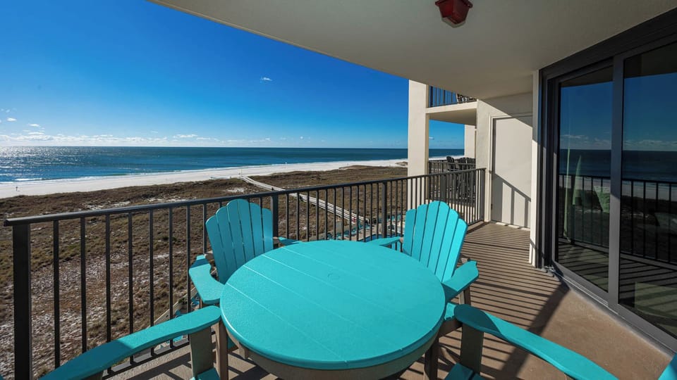 Turquoise outdoor furniture on the balcony offers a perfect spot to relax while enjoying views of the beach and gulf
