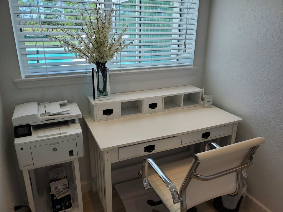 Separate office space with desk, chair and printer.  View of pool.