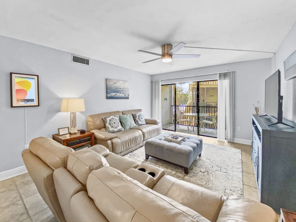 Living room with beige sectional sofa, ceiling fan, and lanai access