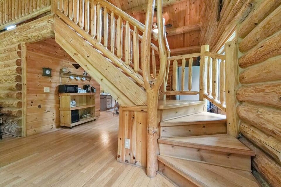 A log staircase leads to the Master Loft area that oversees the front area of the rustic designed cabin.