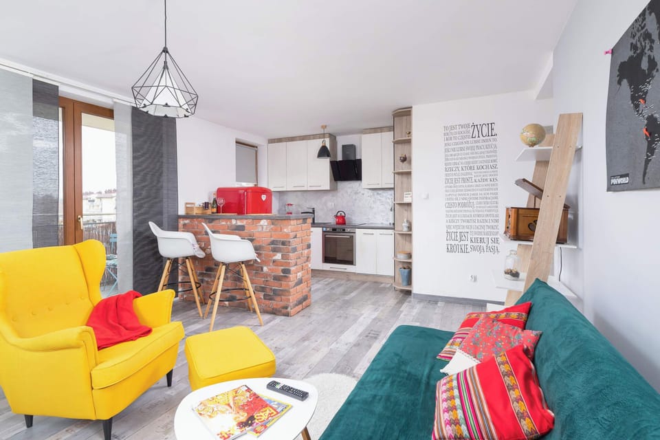 Living room with a sofa bed, TV, desk with a chair and kitchenette.