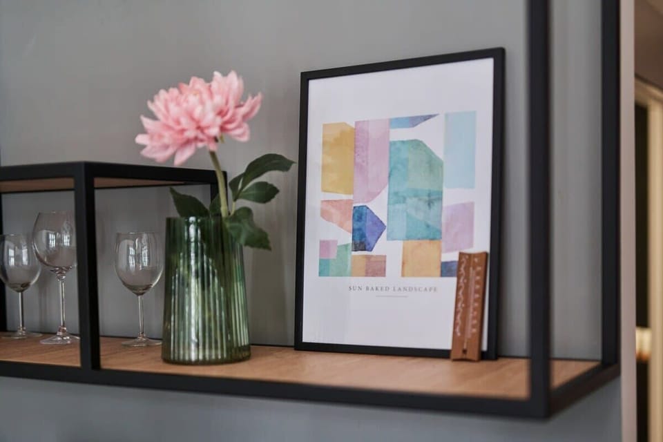 A shelf with small plants and framed art pieces enhancing the space’s aesthetics.
