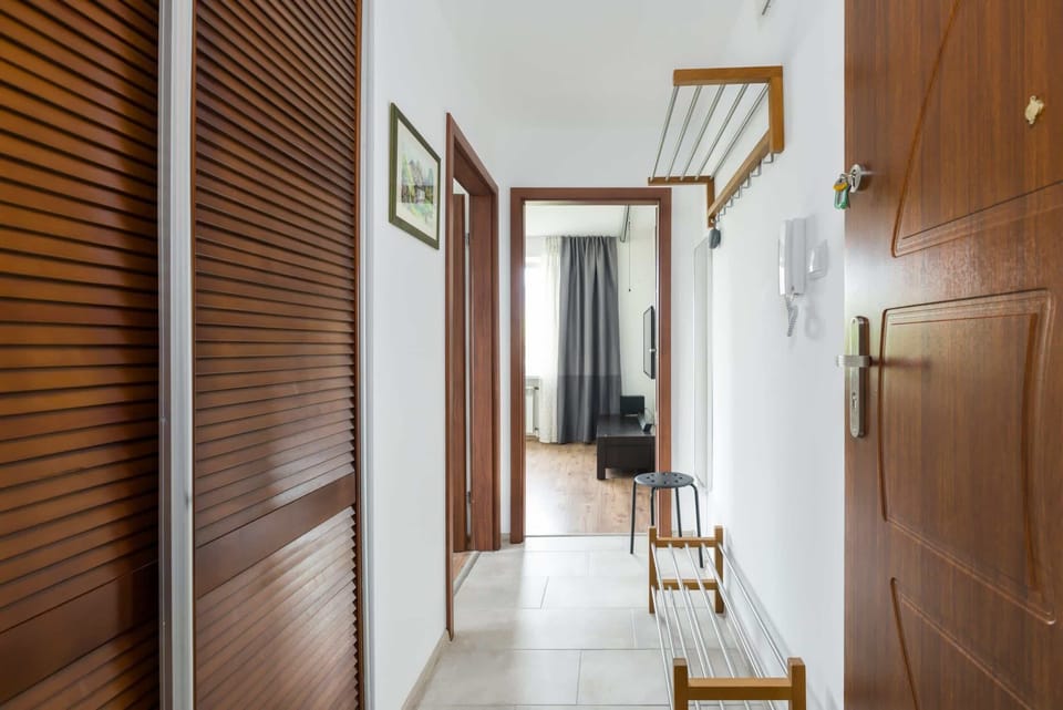 A hallway with wooden-paneled walls, mirrors, and a modern light fixture above.