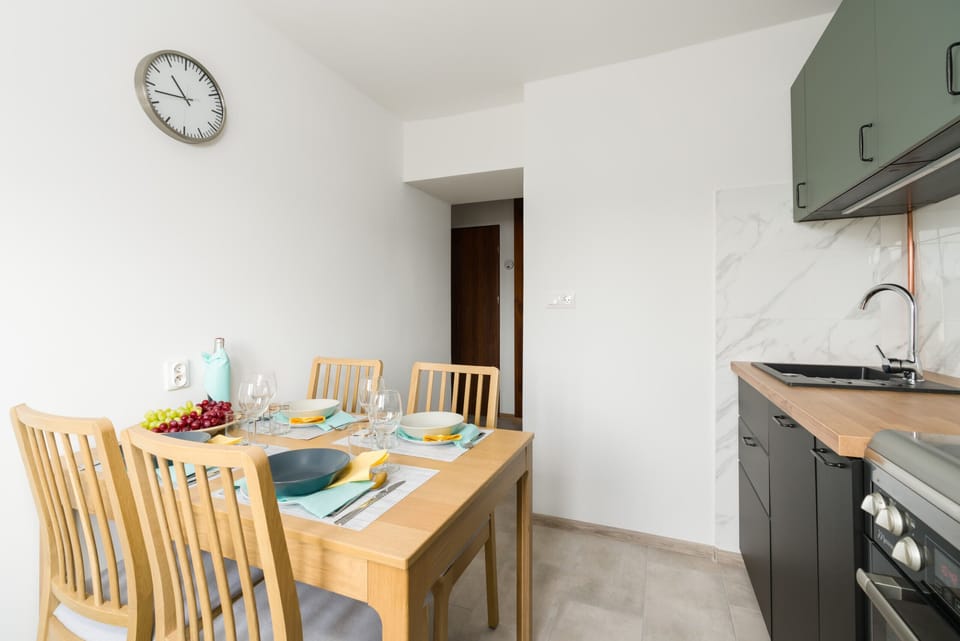 A kitchen and dining space featuring a white table set for four, with a clock on the wall.